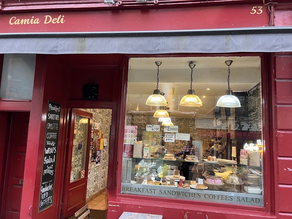 The burgundy shopfront of Camia Delicatessen at 53 Stoke Newington Church Street, with cream lettering and the deli counter visible through the window